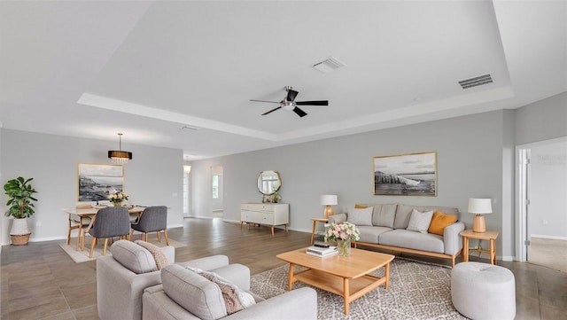 living room featuring a raised ceiling and ceiling fan