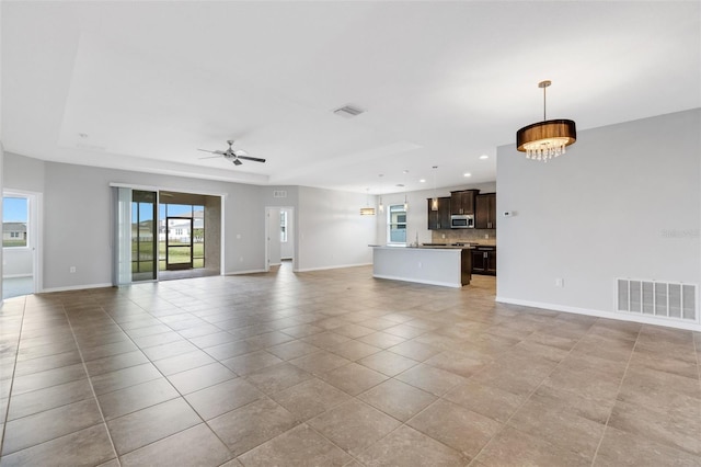 unfurnished living room featuring light tile patterned floors and ceiling fan with notable chandelier