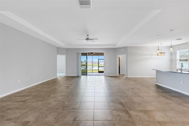 spare room featuring a tray ceiling, ceiling fan, sink, and light tile patterned floors