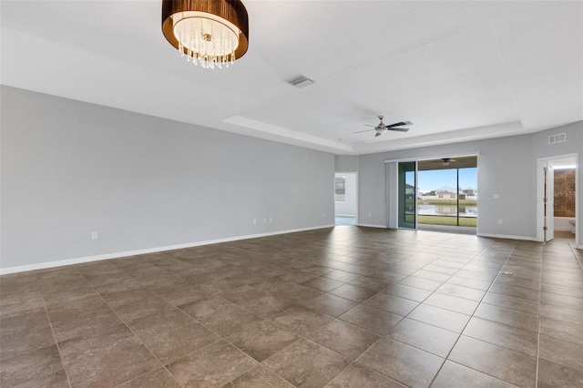 spare room with ceiling fan with notable chandelier and a raised ceiling