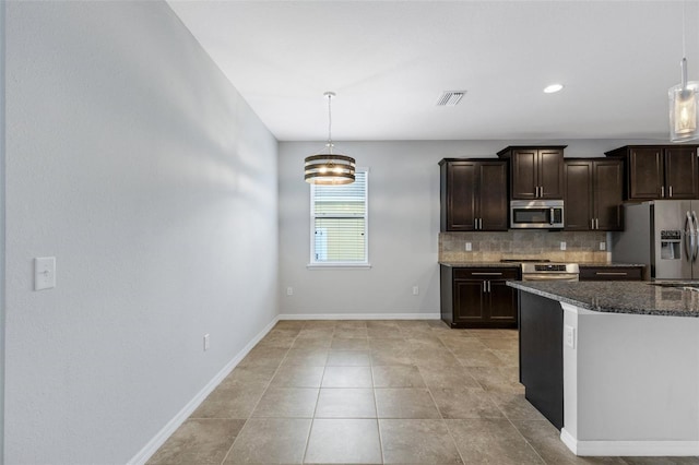 kitchen with dark stone counters, hanging light fixtures, appliances with stainless steel finishes, tasteful backsplash, and dark brown cabinetry