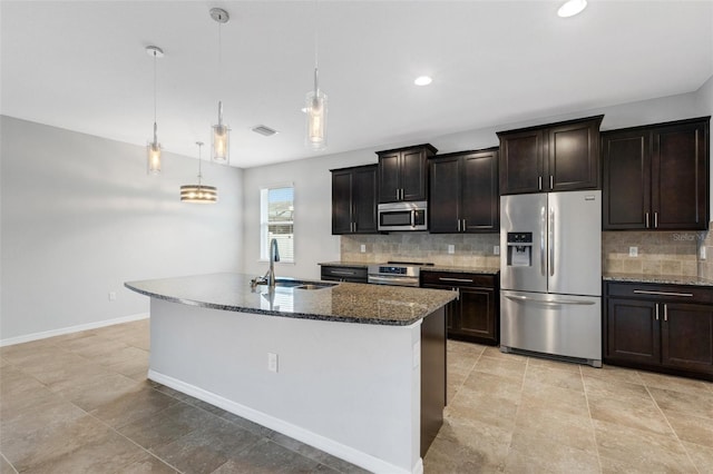 kitchen with decorative light fixtures, sink, stainless steel appliances, and a center island with sink