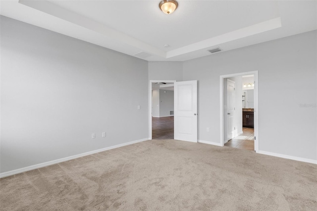 unfurnished bedroom featuring a tray ceiling and light colored carpet