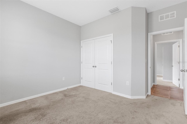 unfurnished bedroom with light colored carpet and a closet