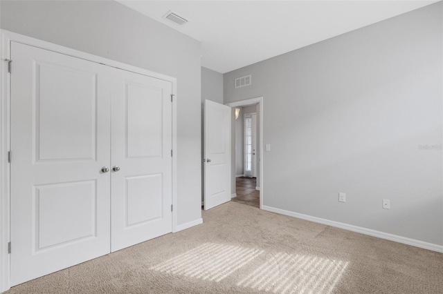 unfurnished bedroom featuring light colored carpet and a closet