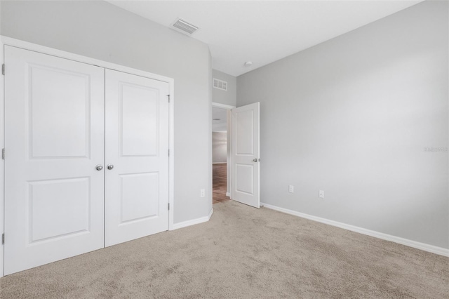 unfurnished bedroom with light colored carpet and a closet