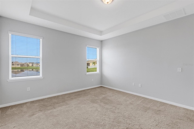 carpeted empty room featuring a tray ceiling