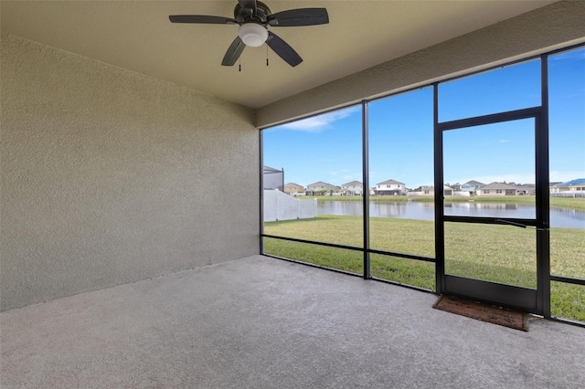 unfurnished sunroom with ceiling fan and a water view