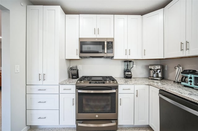 kitchen with appliances with stainless steel finishes, white cabinetry, and light stone counters