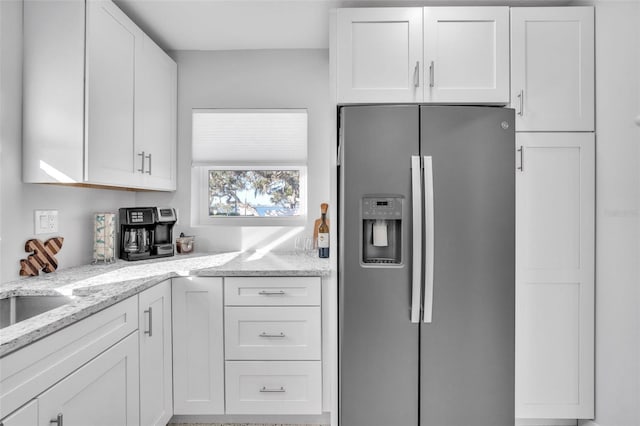 kitchen with white cabinets, stainless steel fridge, and light stone countertops