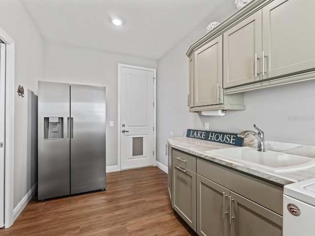 kitchen with light stone countertops, gray cabinetry, dark wood-type flooring, sink, and stainless steel fridge with ice dispenser