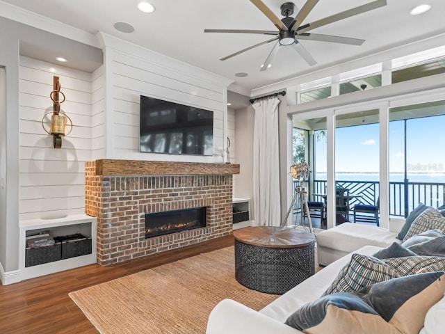 living room with hardwood / wood-style floors, a brick fireplace, and ceiling fan