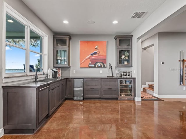 bar with dark brown cabinets, sink, and wine cooler