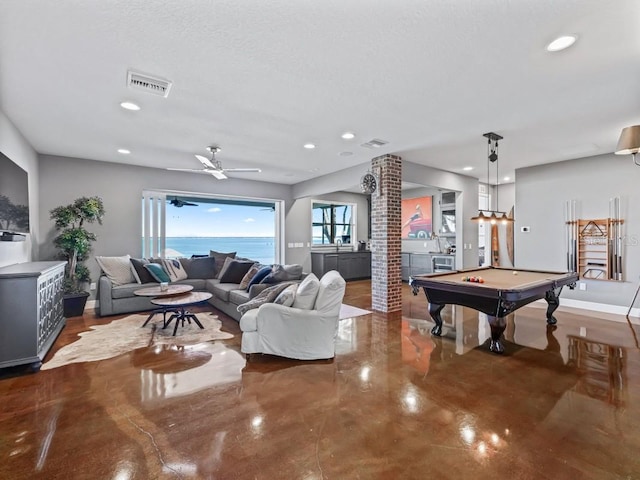 living room featuring decorative columns, ceiling fan, a water view, billiards, and concrete floors