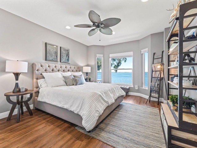 bedroom with a water view, ceiling fan, and dark wood-type flooring