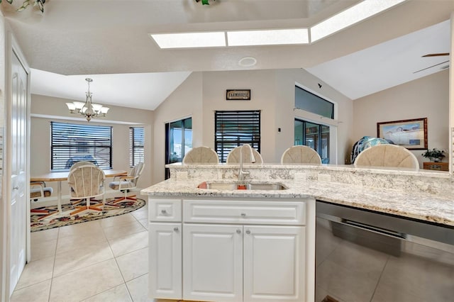 kitchen featuring stainless steel dishwasher, white cabinets, sink, and vaulted ceiling