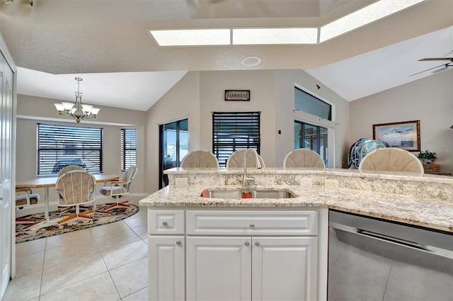 kitchen featuring pendant lighting, lofted ceiling, sink, stainless steel dishwasher, and white cabinetry