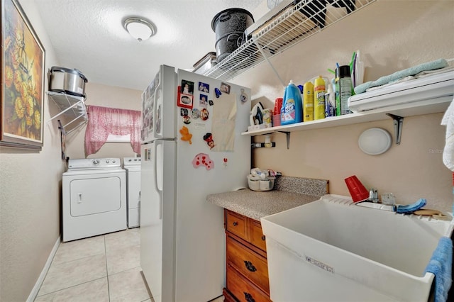 laundry room featuring separate washer and dryer, sink, light tile patterned floors, and a textured ceiling