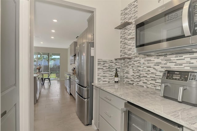 kitchen featuring decorative backsplash, light stone counters, stainless steel appliances, and beverage cooler