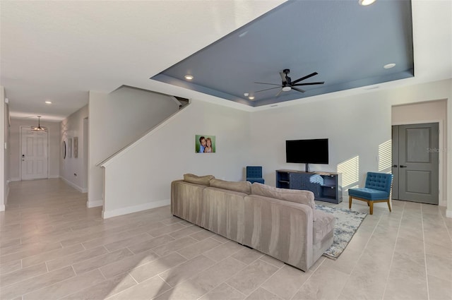 living room with a raised ceiling and ceiling fan