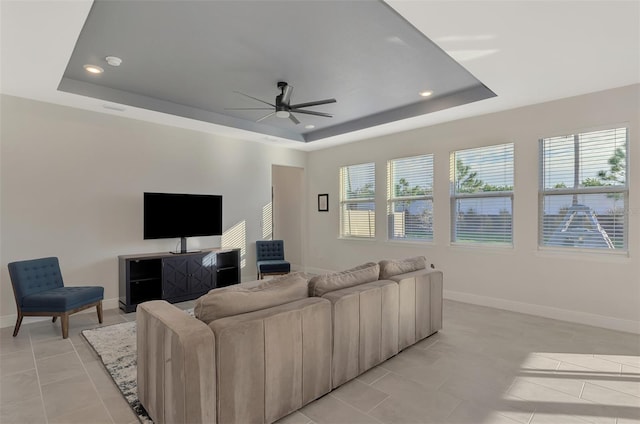 living room with ceiling fan, light tile patterned floors, and a tray ceiling