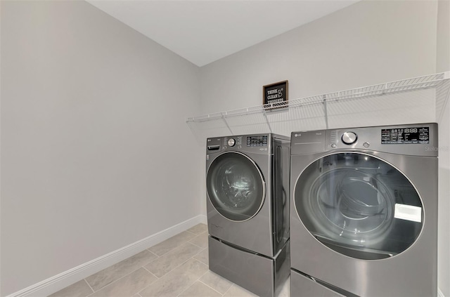 clothes washing area with washing machine and clothes dryer and light tile patterned floors