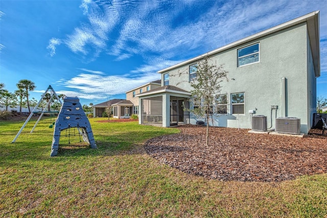 back of house featuring a playground, a sunroom, a yard, and cooling unit