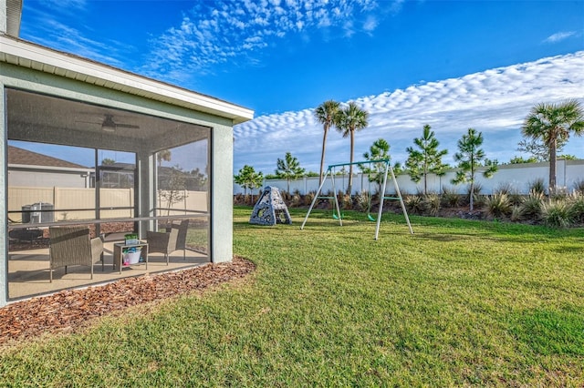 view of yard with a playground, a sunroom, ceiling fan, and a patio