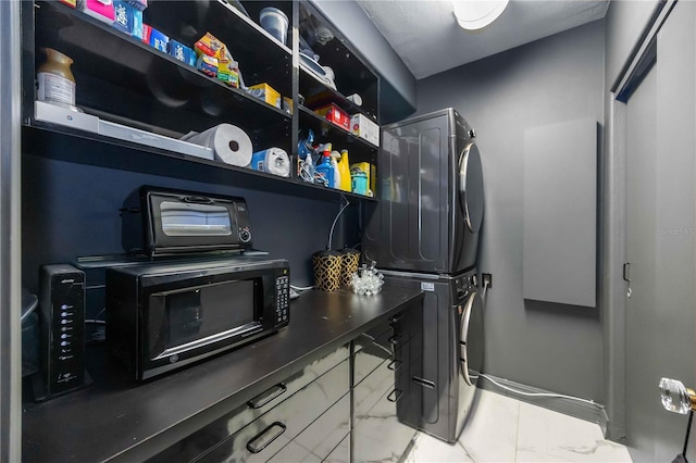 clothes washing area featuring marble finish floor, laundry area, and stacked washer and clothes dryer