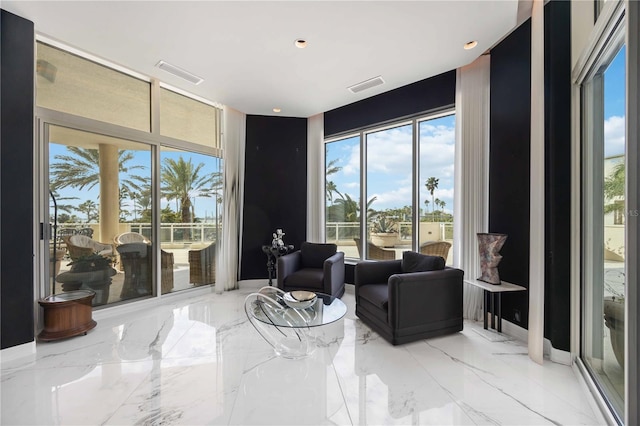 sitting room with marble finish floor, visible vents, and floor to ceiling windows