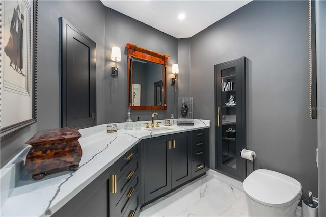 bathroom with marble finish floor, vanity, and toilet