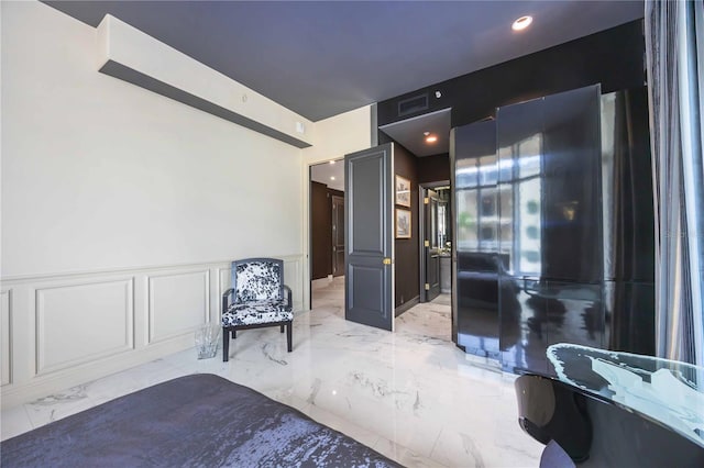 unfurnished bedroom with marble finish floor, visible vents, a decorative wall, and wainscoting