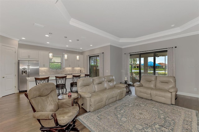 living room with a tray ceiling, crown molding, and wood-type flooring