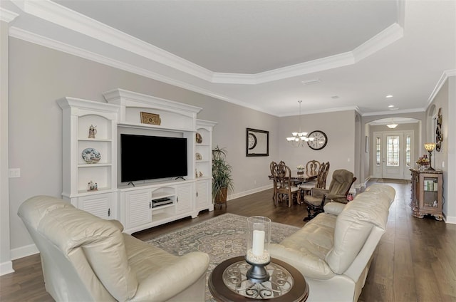 living room featuring dark hardwood / wood-style floors, a raised ceiling, ornamental molding, and a notable chandelier