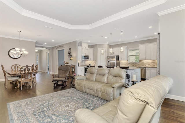 living room with a notable chandelier, dark hardwood / wood-style floors, ornamental molding, and a tray ceiling