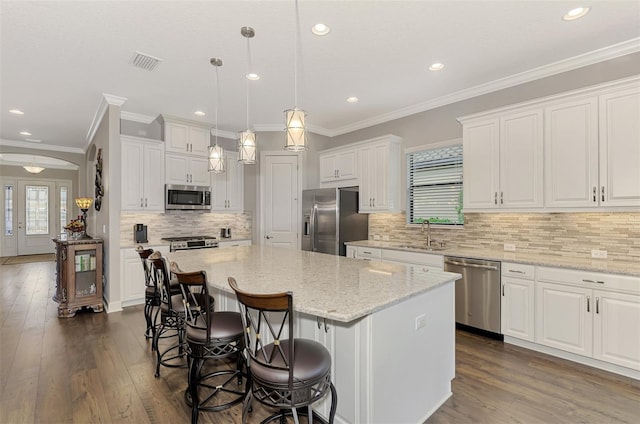 kitchen featuring white cabinets, stainless steel appliances, a kitchen island, and hanging light fixtures