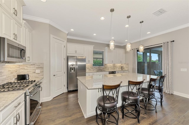 kitchen featuring pendant lighting, a kitchen island, white cabinets, and stainless steel appliances