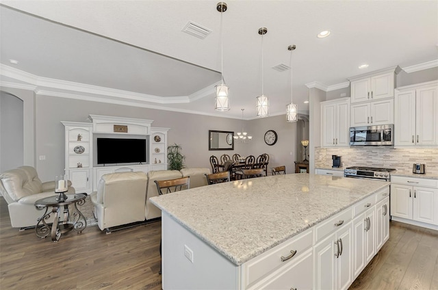 kitchen featuring tasteful backsplash, decorative light fixtures, a kitchen island, white cabinetry, and stainless steel appliances