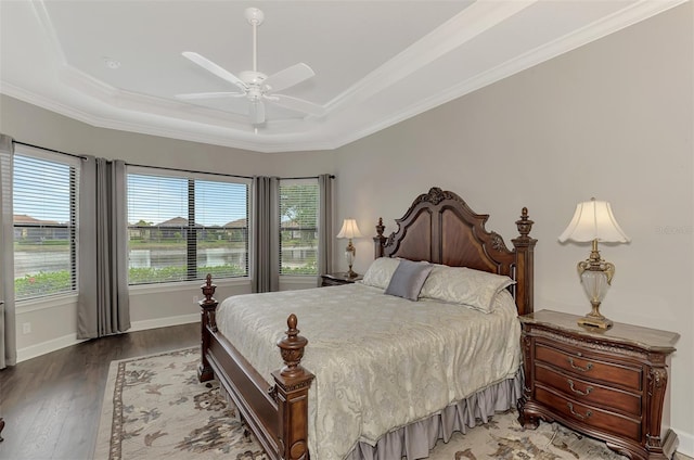 bedroom with hardwood / wood-style floors, ceiling fan, ornamental molding, and a tray ceiling