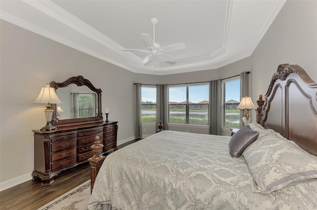 bedroom featuring ceiling fan, crown molding, dark wood-type flooring, and a tray ceiling