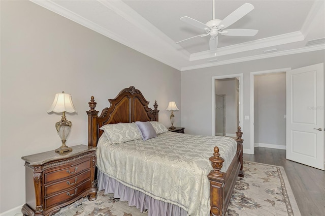 bedroom featuring a tray ceiling, ceiling fan, crown molding, and light hardwood / wood-style floors