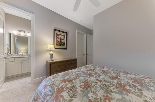 bedroom featuring light carpet, ensuite bath, and ceiling fan