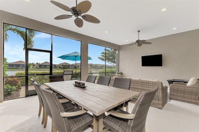 dining space with ceiling fan and a water view