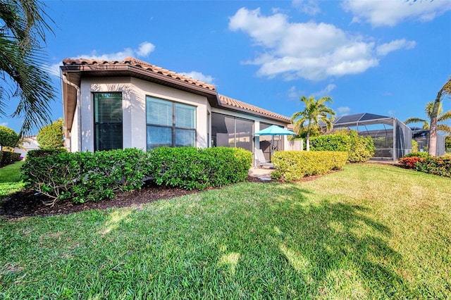 view of home's exterior featuring a lawn and glass enclosure