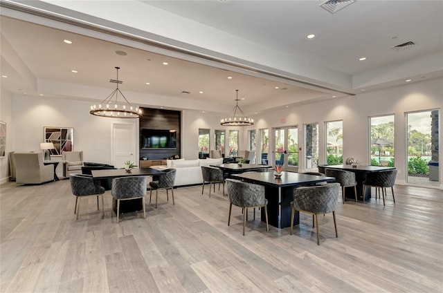 dining area with a chandelier, french doors, light wood-type flooring, and a tray ceiling