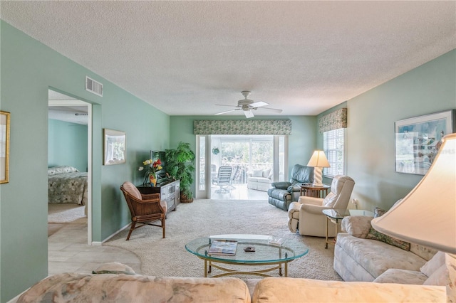 living room featuring ceiling fan, light colored carpet, and a textured ceiling