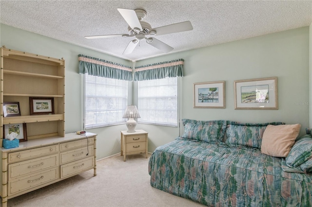 bedroom featuring multiple windows, a textured ceiling, light colored carpet, and ceiling fan