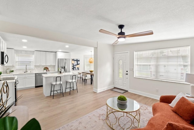 living room with ceiling fan, sink, and light hardwood / wood-style floors