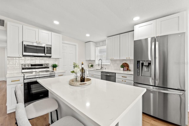 kitchen featuring a kitchen island, white cabinets, light wood-type flooring, and appliances with stainless steel finishes