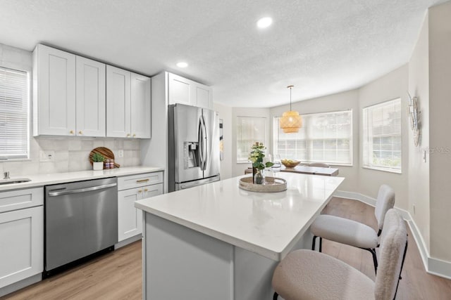 kitchen with pendant lighting, a center island, white cabinets, decorative backsplash, and appliances with stainless steel finishes